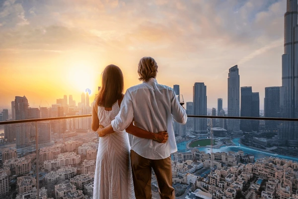 Couple embraces on a high-rise balcony, watching the sun set over downtown Austin.