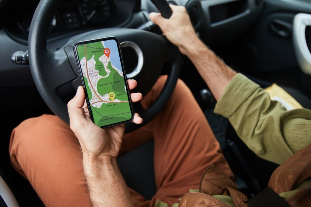 Man using a smartphone navigation app while driving on a scenic road trip — perfect for GPS-based travel planning with Travel Crock