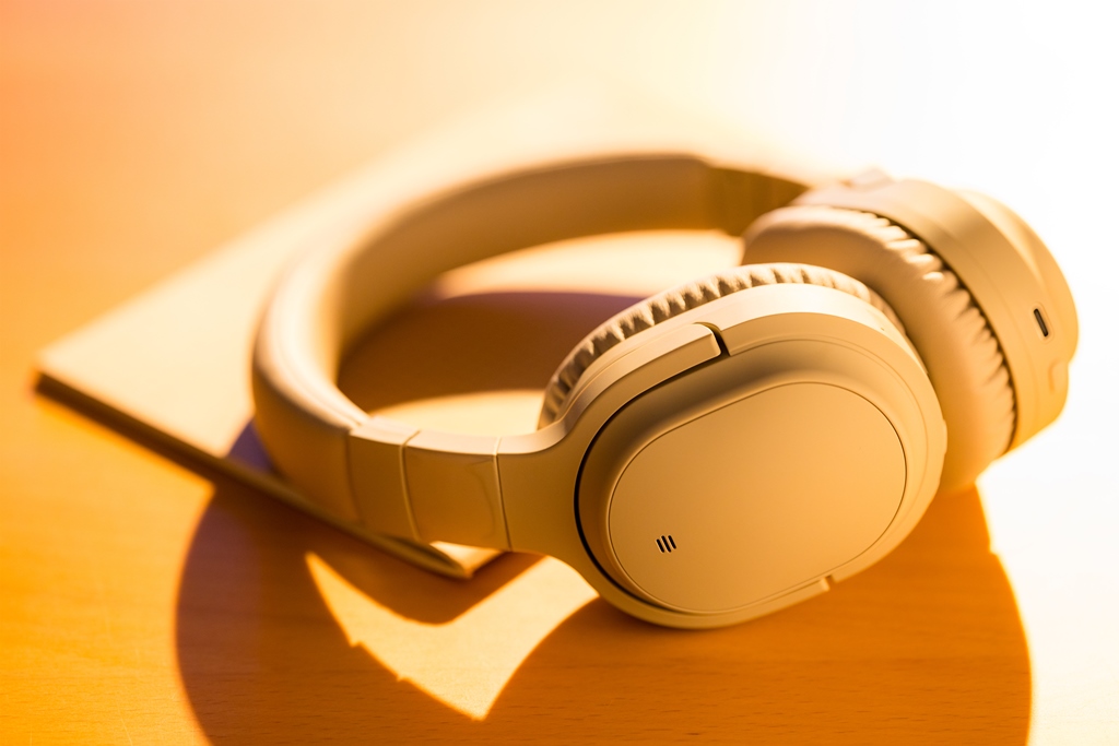 Beige noise-canceling headphones resting on a notebook under warm sunlight—ideal for peaceful travel experiences with Travel Crock