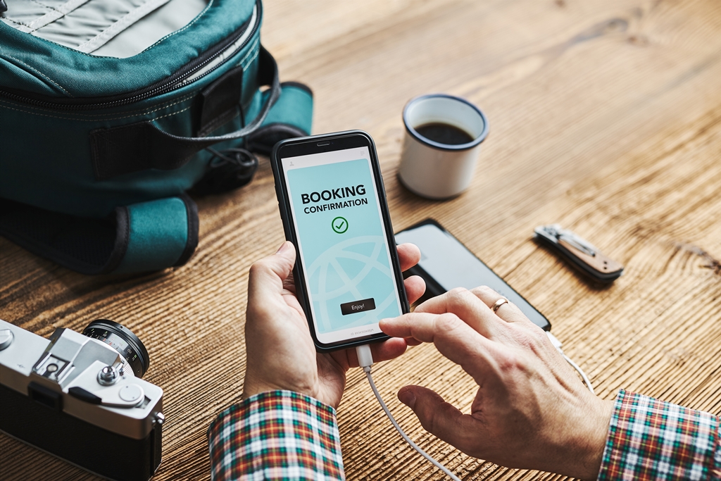 Traveler confirming hotel booking on smartphone with travel gear on table—perfect visual for smart trip planning with Travel Crock