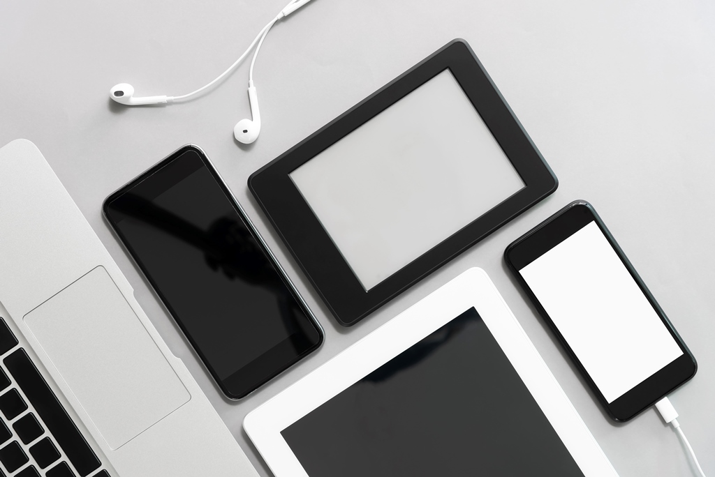 Flat lay of tech gadgets including e-readers, tablets, smartphones, laptop, and earphones—perfect travel-ready digital tools with Travel Crock