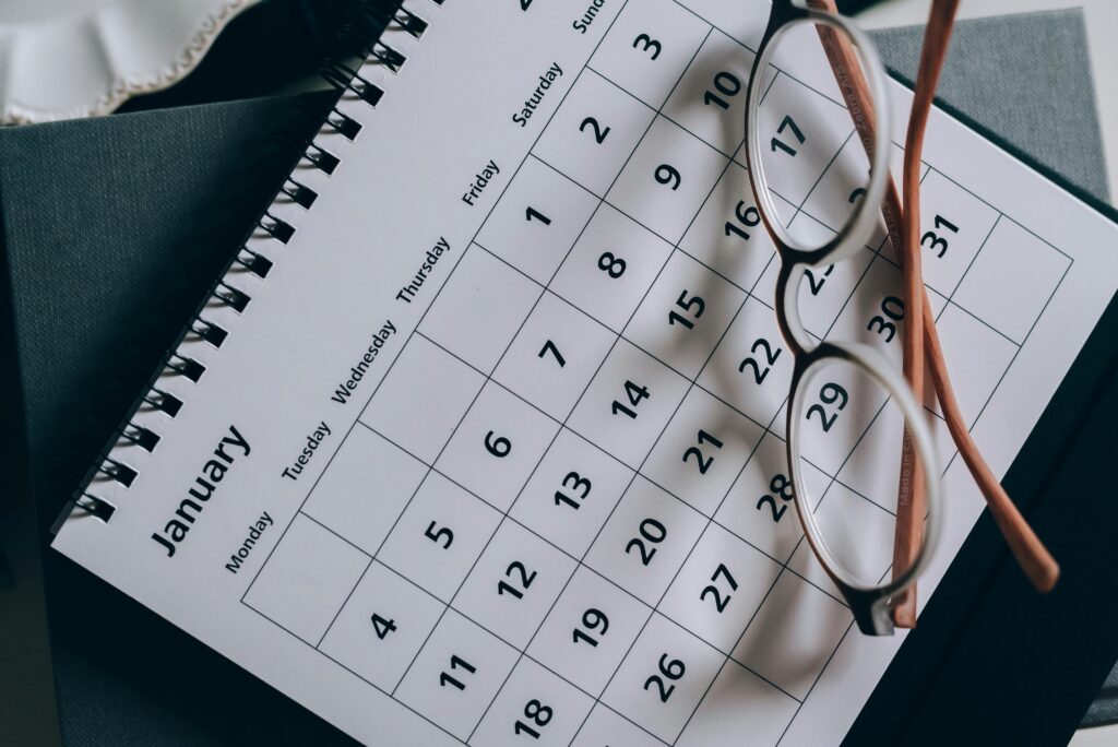 Close-up of a January calendar with eyeglasses resting on it, symbolizing travel date planning and the importance of flexible scheduling.