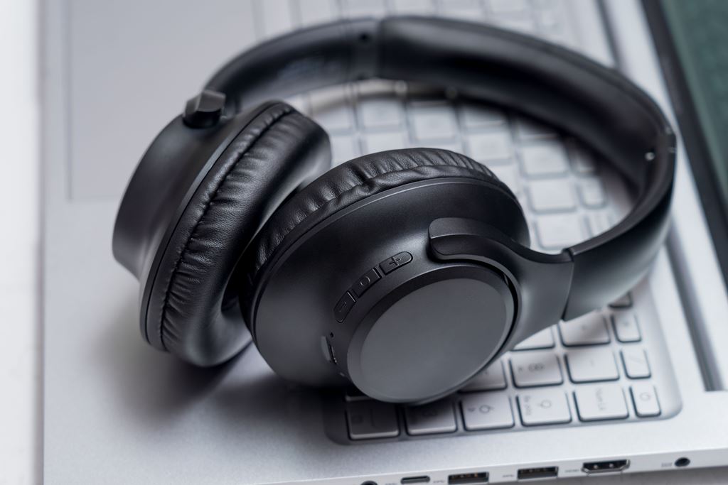 Black noise-canceling headphones resting on a laptop—ideal tech for blocking out noise during long flights, featured by Travel Crock.