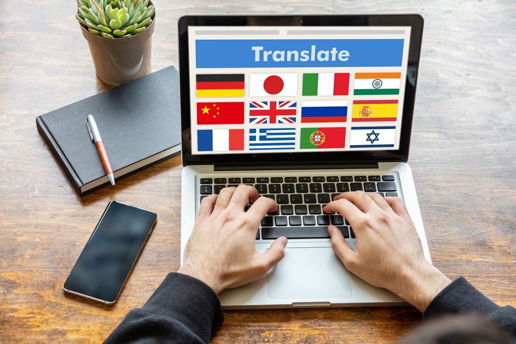 "Person typing on a laptop with multiple country flags and the word 'Translate' on screen, symbolizing global translation and localization services"
