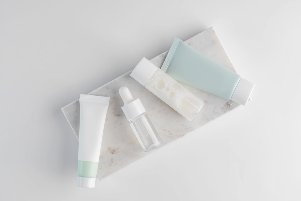Minimalist travel-size skincare products on marble—moisturizer, serum, and lotion essentials for dry skin relief on long flights by Travel Crock.