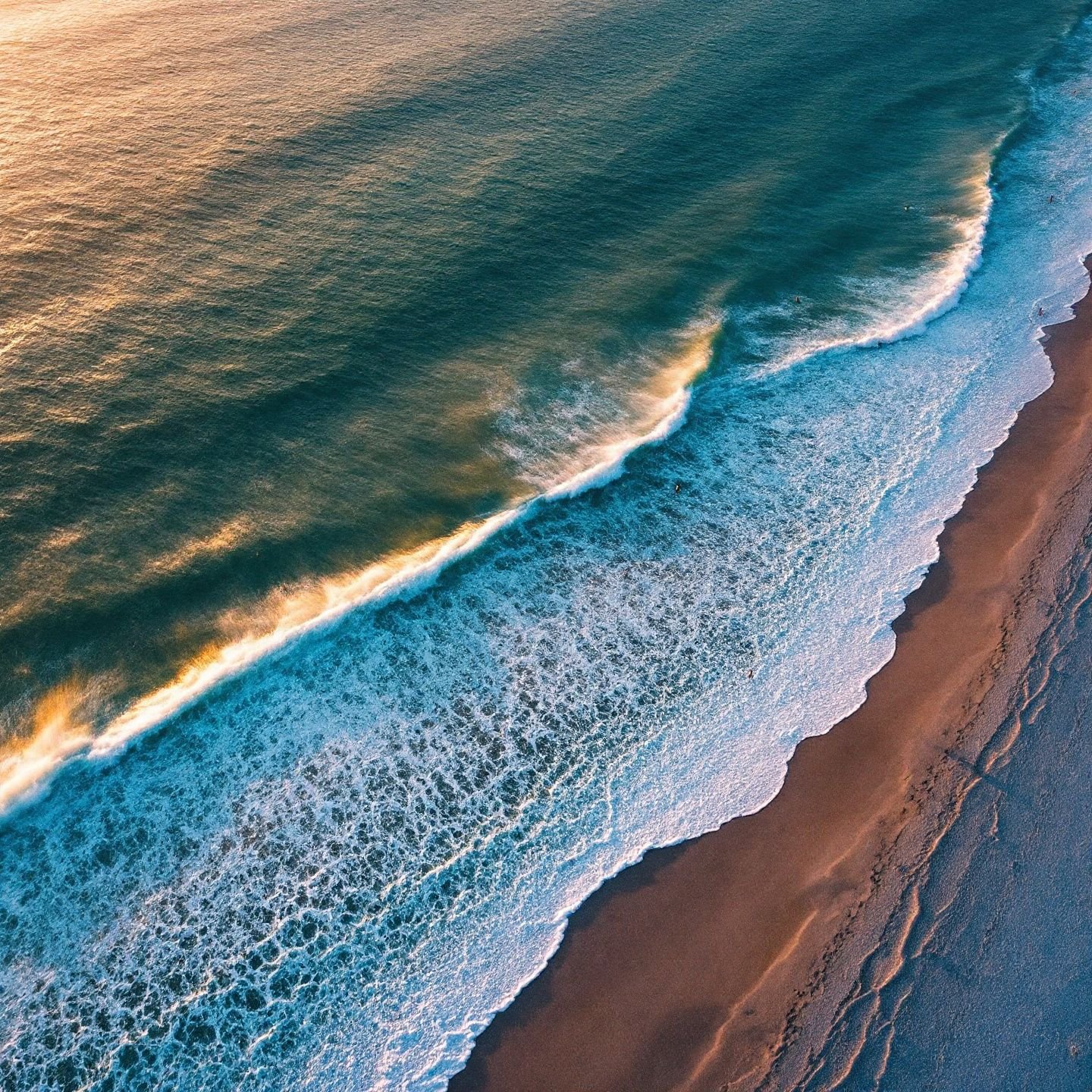 Aerial view of Cocoa Beach at sunrise with golden waves